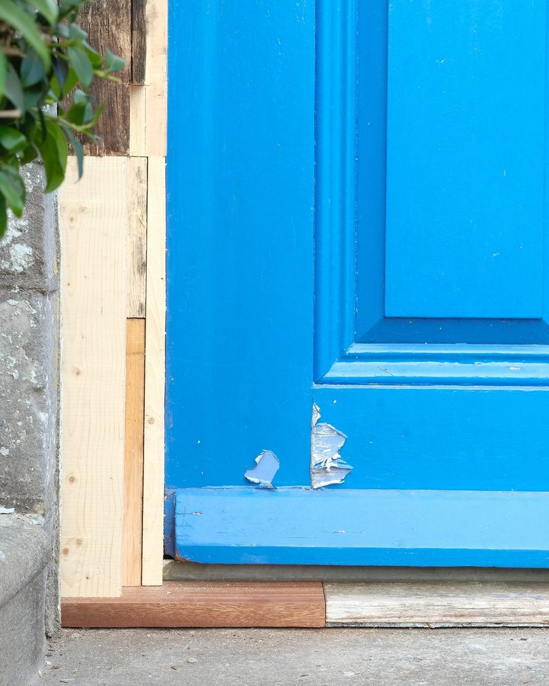 New timber spliced into the foot of a rotten door frame, above a new hardwood threshold