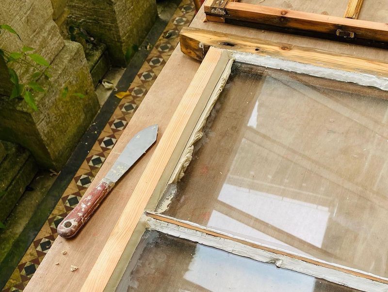 New linseed oil putty going in around the original glass, with a putty knife beside it