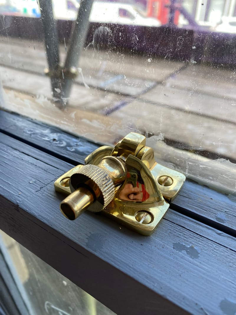 The same brass sash fastener, closed