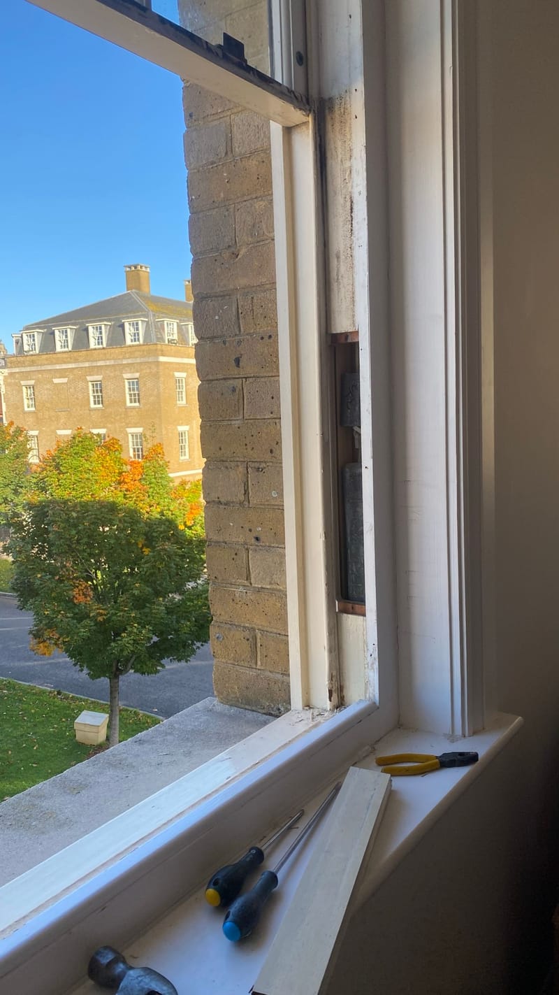 Sash window being repaired in place, with tools on the cill