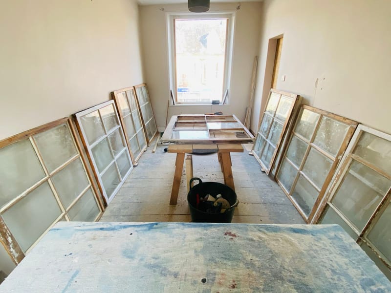 A whole house’s sashes taken out and lined up in a room for restoration